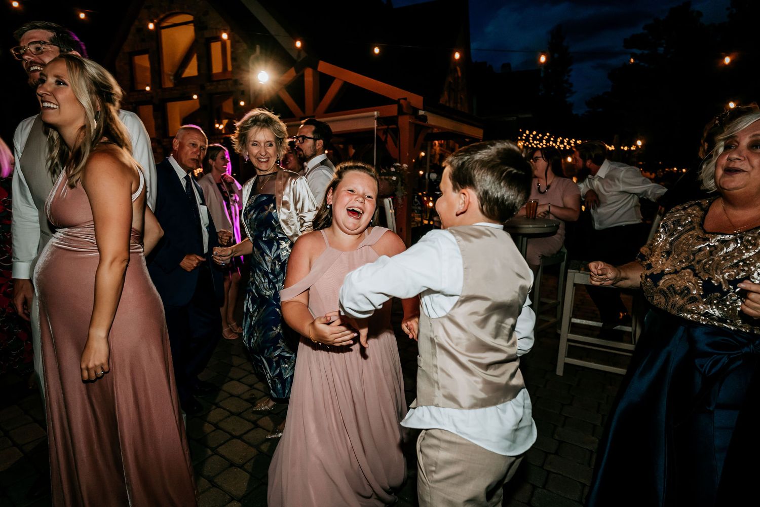 Wedding reception dance party at night with festive lighting and dancing guests.