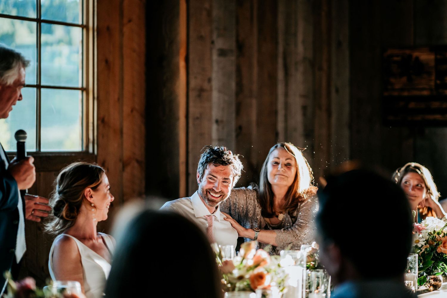 Joyful laughter fills the room during reception speeches at an elegant indoor celebration.