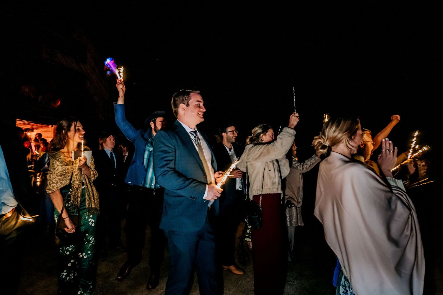 Wedding celebration at night with guests dancing while holding illuminated wands.