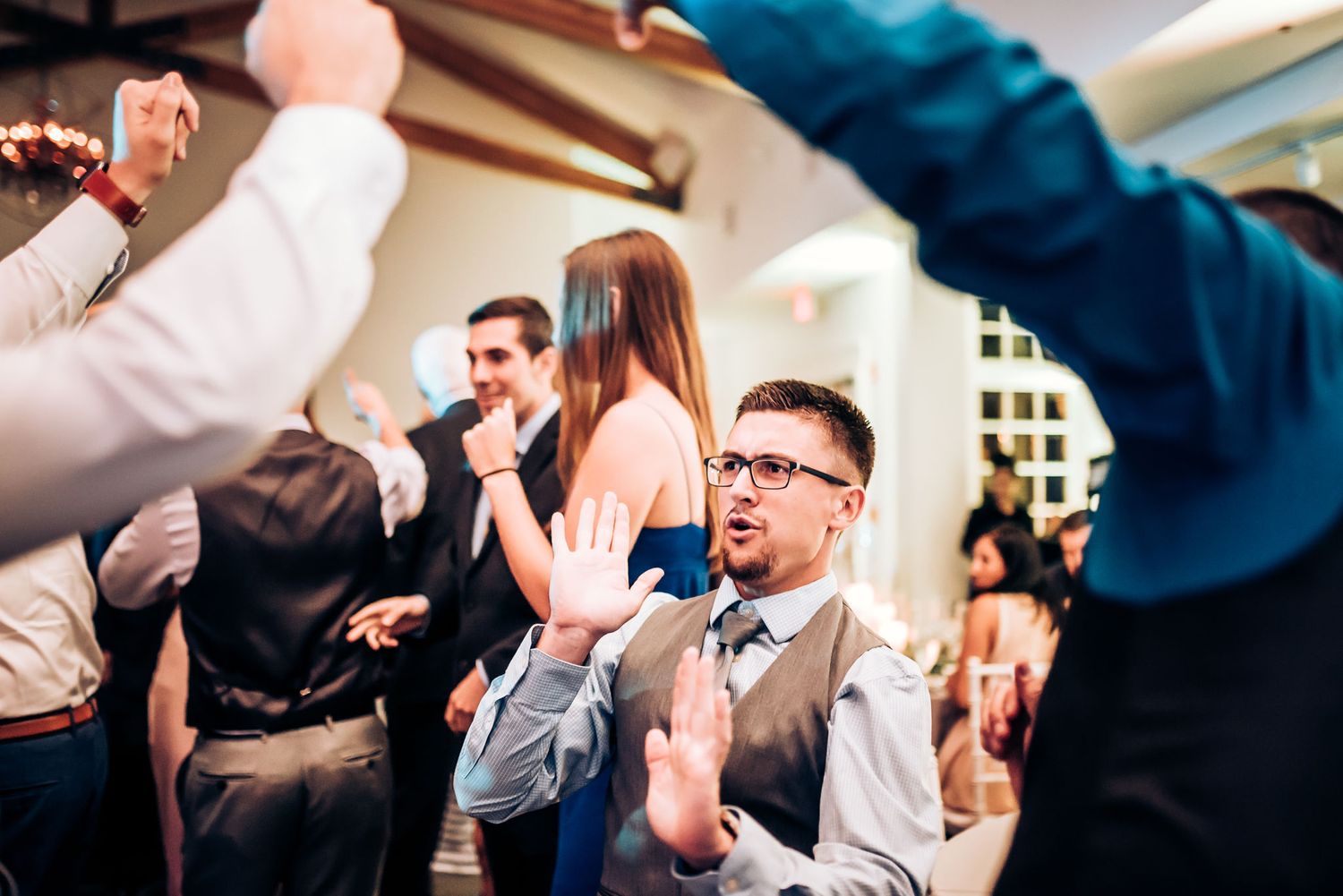 Wedding guests celebrate enthusiastically on a packed dance floor during the reception.