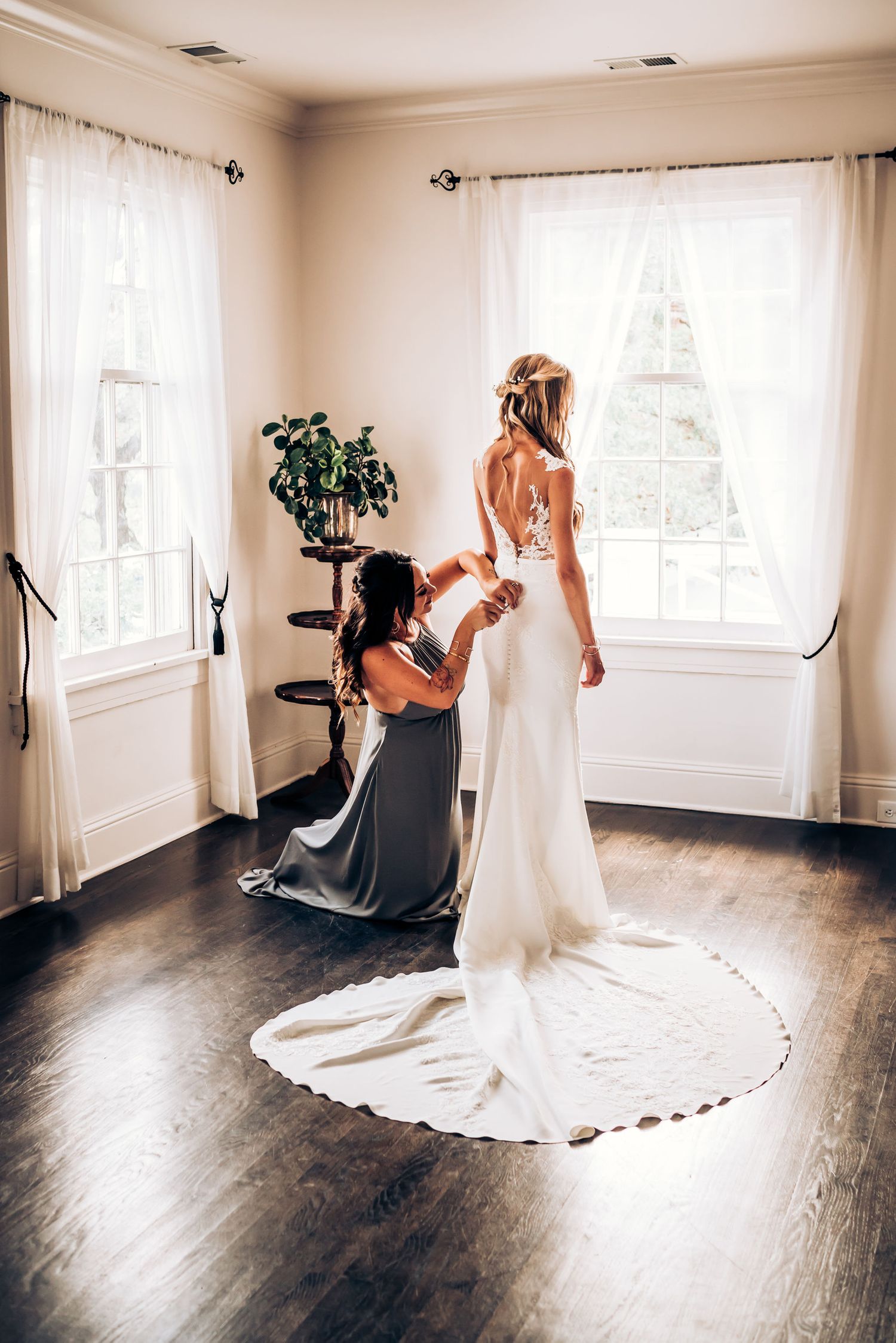 Elegant wedding dress with long train displayed in bright corner room.