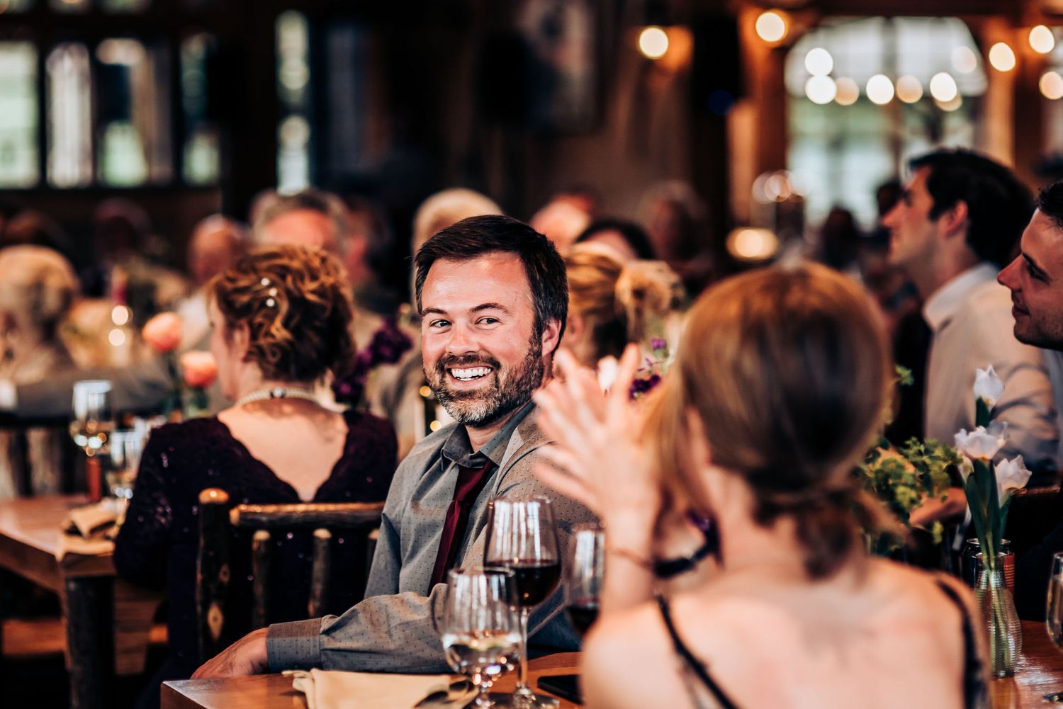Reception guests enjoying dinner and conversation in a warmly lit restaurant setting.