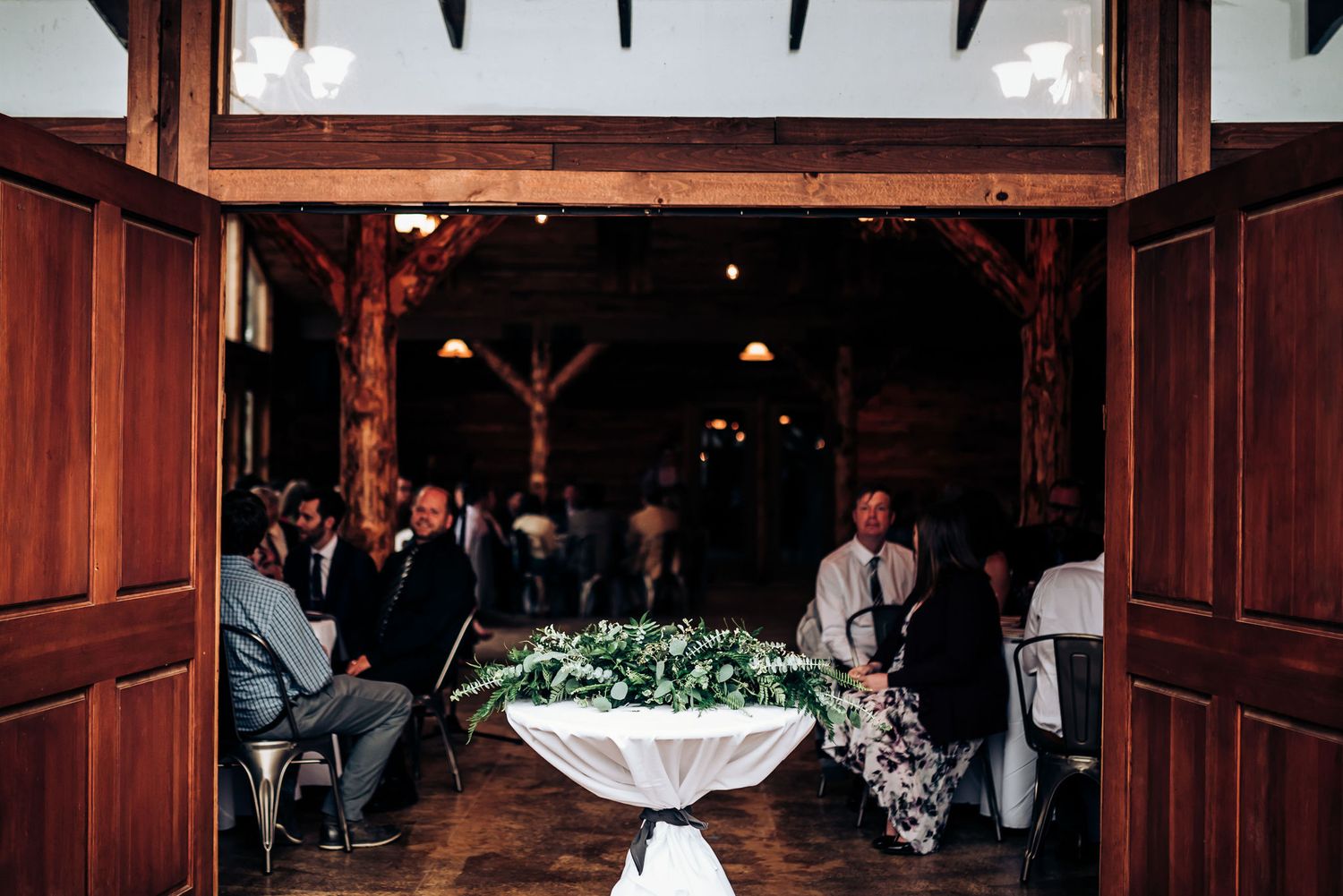 A wedding reception setup in a rustic wooden venue with floral centerpiece.