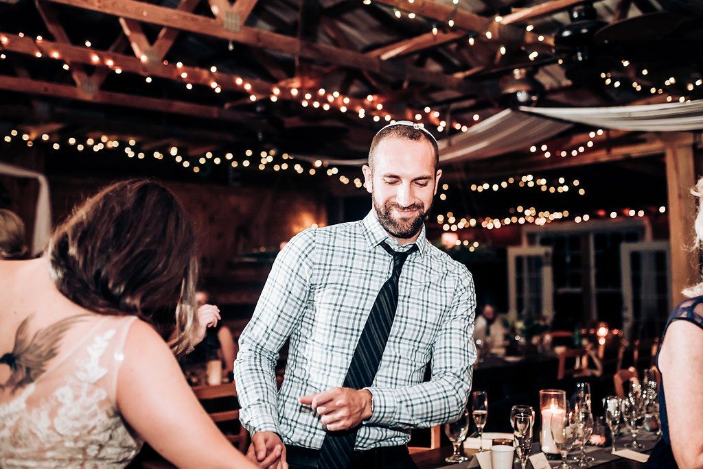 Wedding guests chat and mingle during the reception under decorative string lights.