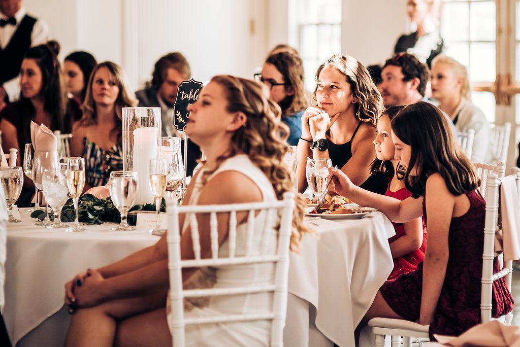 Wedding guests enjoying themselves at elegantly decorated reception tables with champagne glasses.