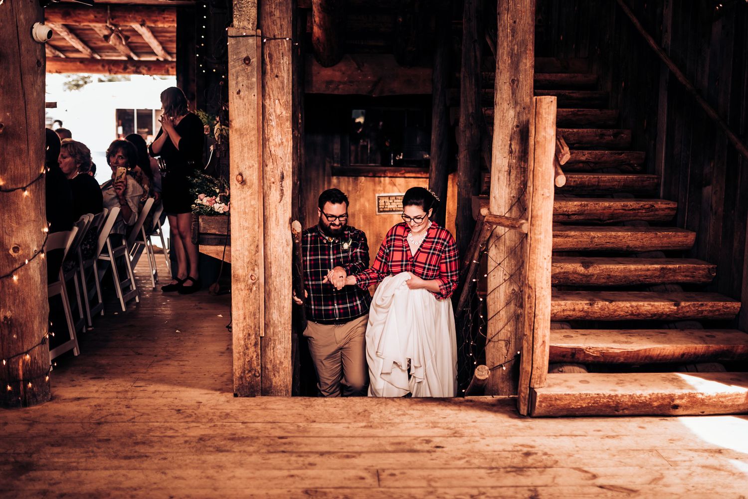 Rustic wooden staircase and hallway filled with wedding attendees.