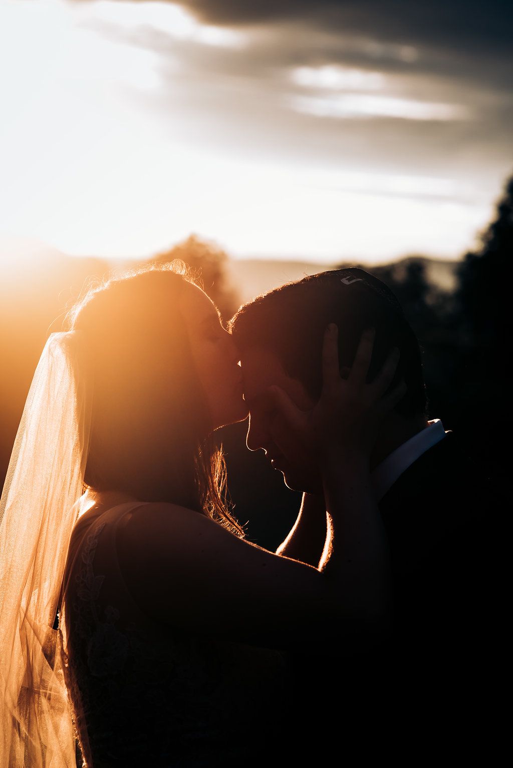 Silhouetted couple sharing intimate moment during golden hour.
