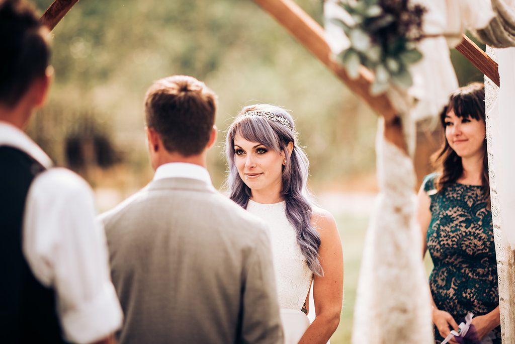 An outdoor wedding moment captured under a rustic wooden arch with floral decorations.