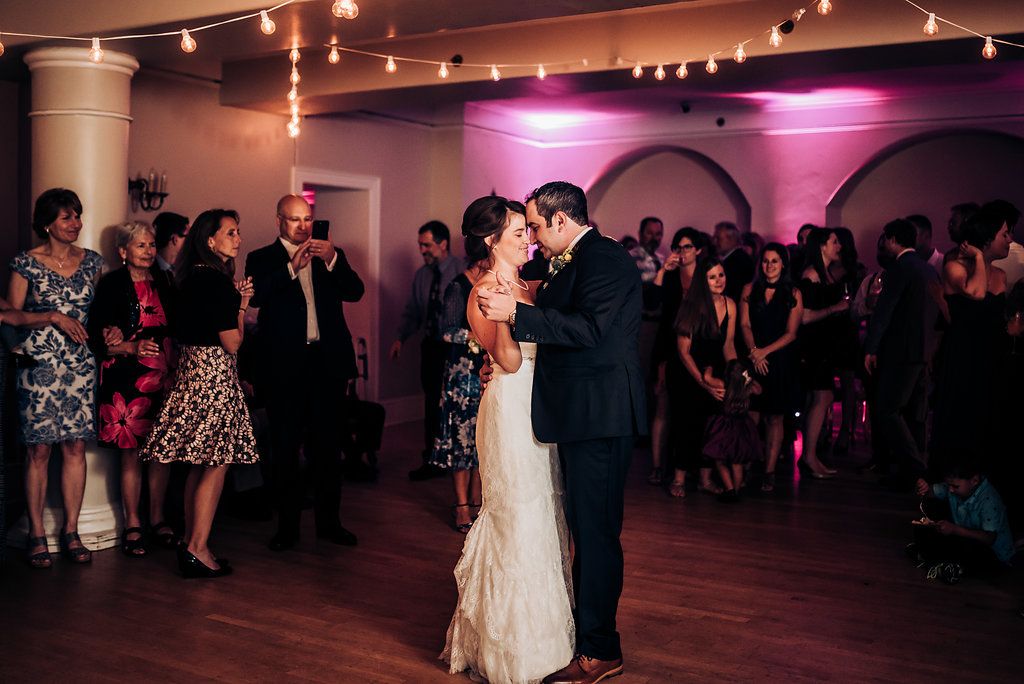 Couple shares first dance under romantic string lights at wedding reception.