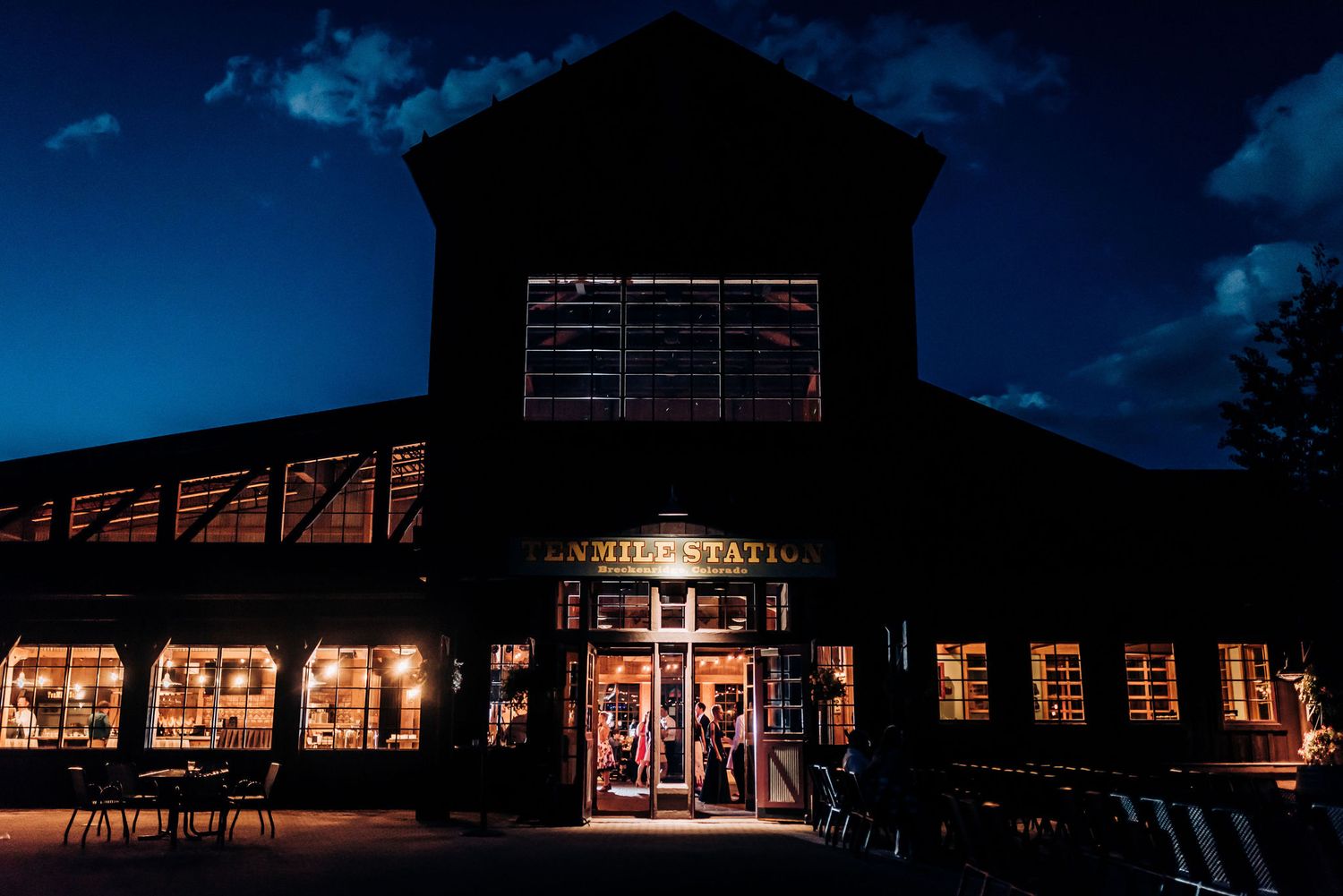 Illuminated barn venue exterior glows against deep blue twilight sky with welcoming entrance.