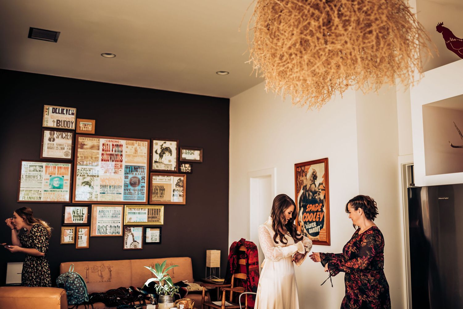 Wedding preparation scene in a modern room with photo wall decor and chandelier.