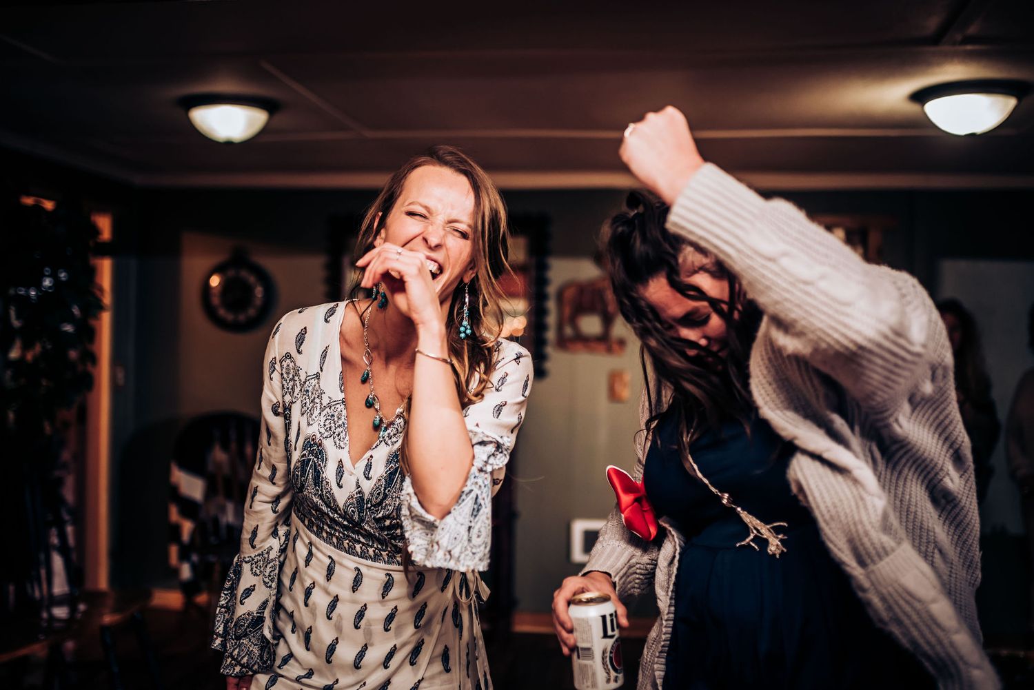 Revelers enjoying music and dancing in a rustic wood-paneled room with ceiling lights.