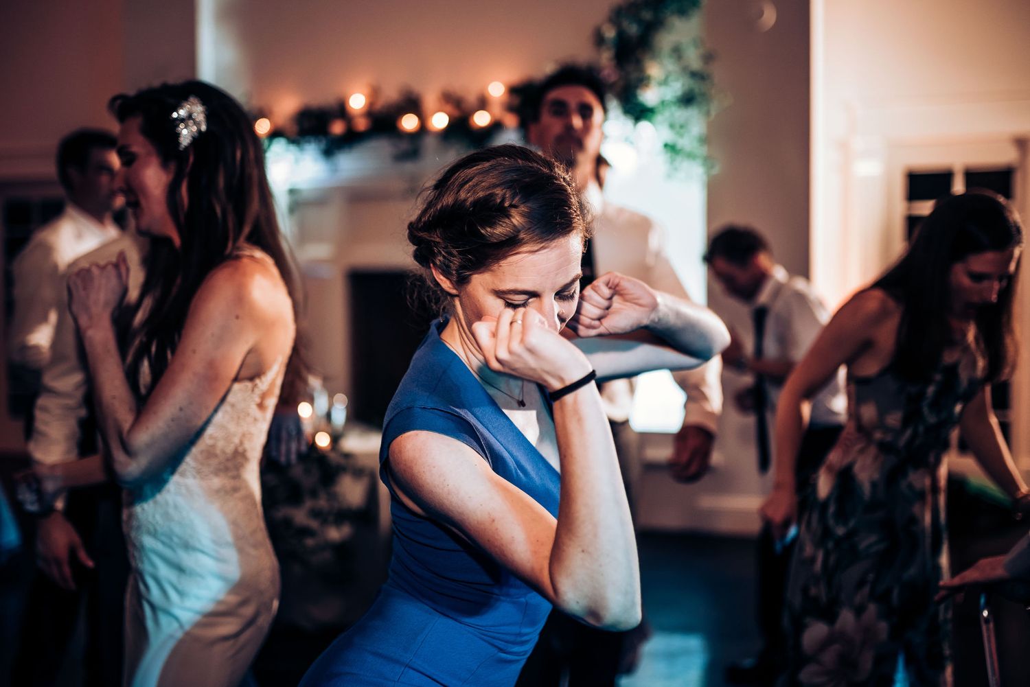 Party guest in blue dress dances enthusiastically at evening celebration.