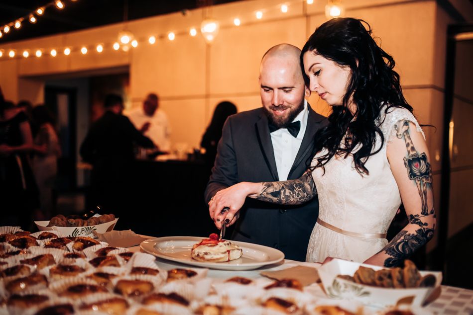 A couple enjoying desserts at their wedding reception with a display of treats.