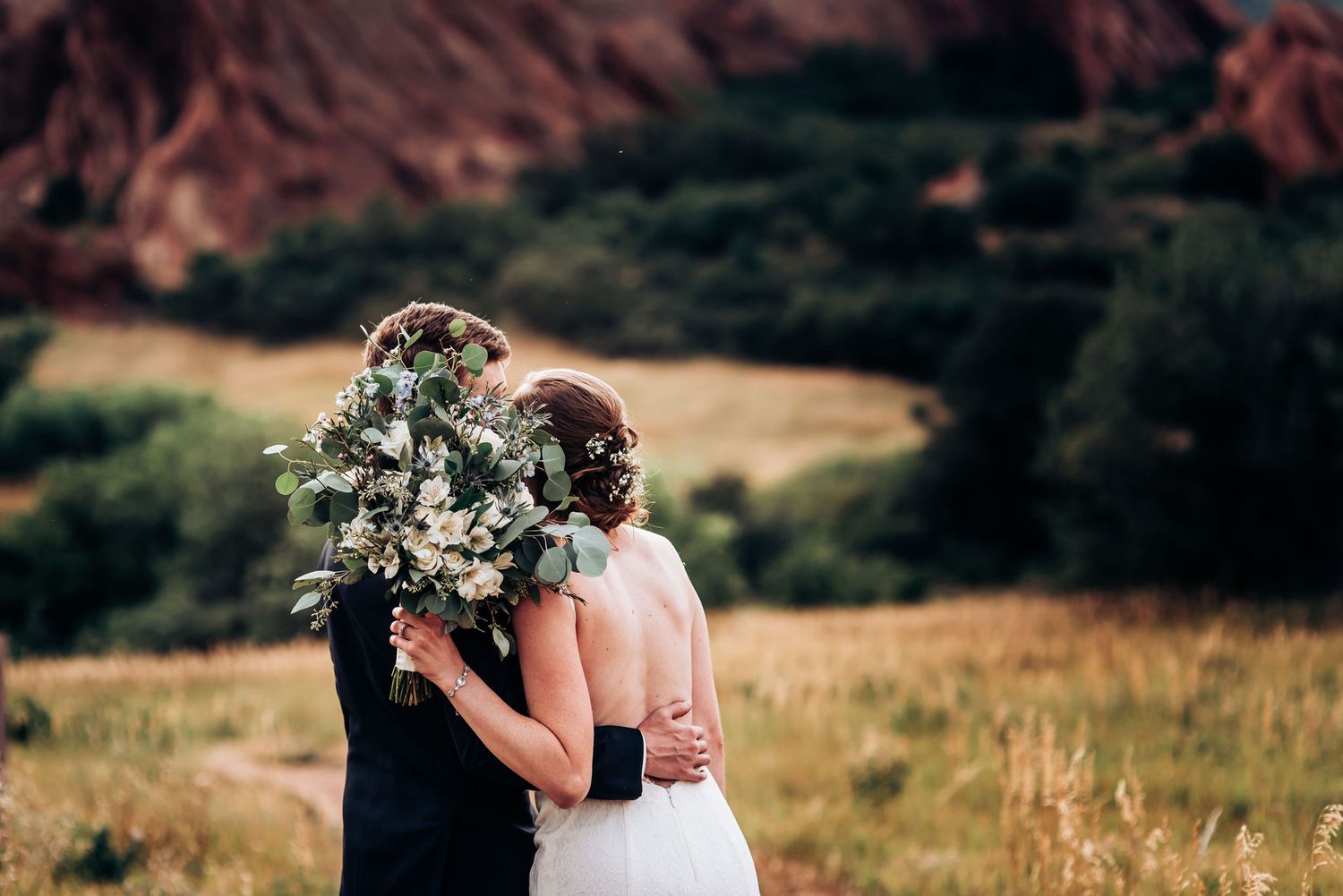 A couple shares an intimate moment with mountain views and a eucalyptus bouquet.