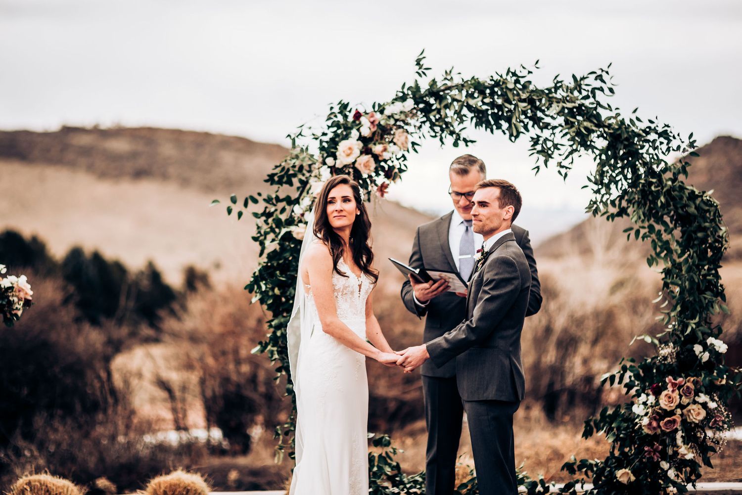 Wedding ceremony under a beautiful floral arch with mountains and winter landscape in the background.