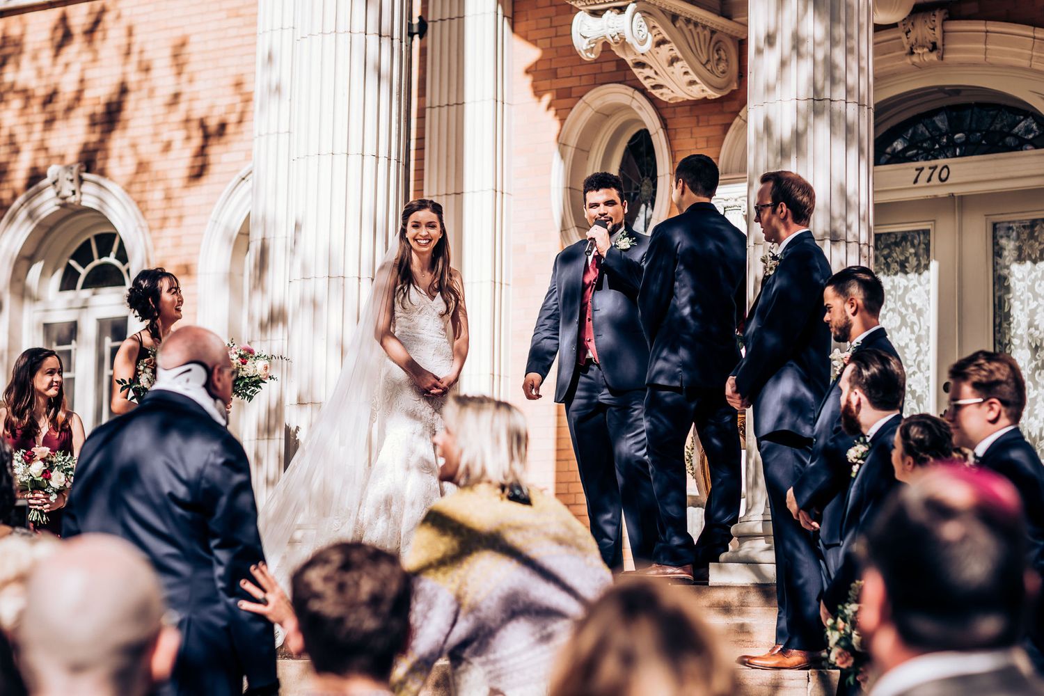 Wedding ceremony on the steps of a grand historic building with columns and architectural details.
