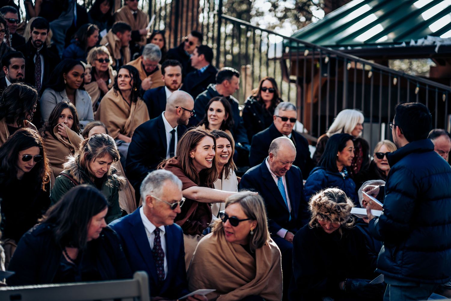 Elegantly dressed crowd gathered at an outdoor winter wedding ceremony in the mountains.