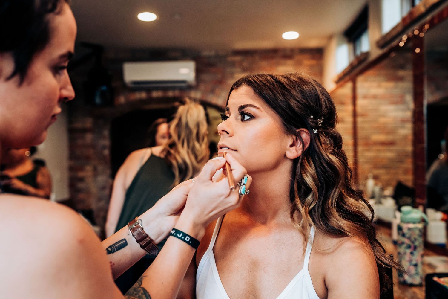 A makeup artist applies cosmetics during wedding preparations.