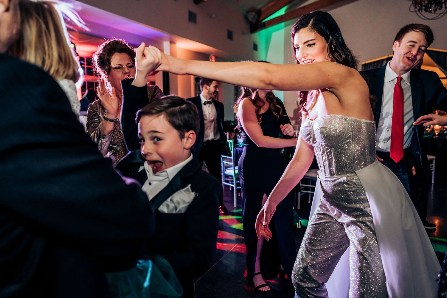 Energetic dancing during a wedding reception with colorful lighting effects.
