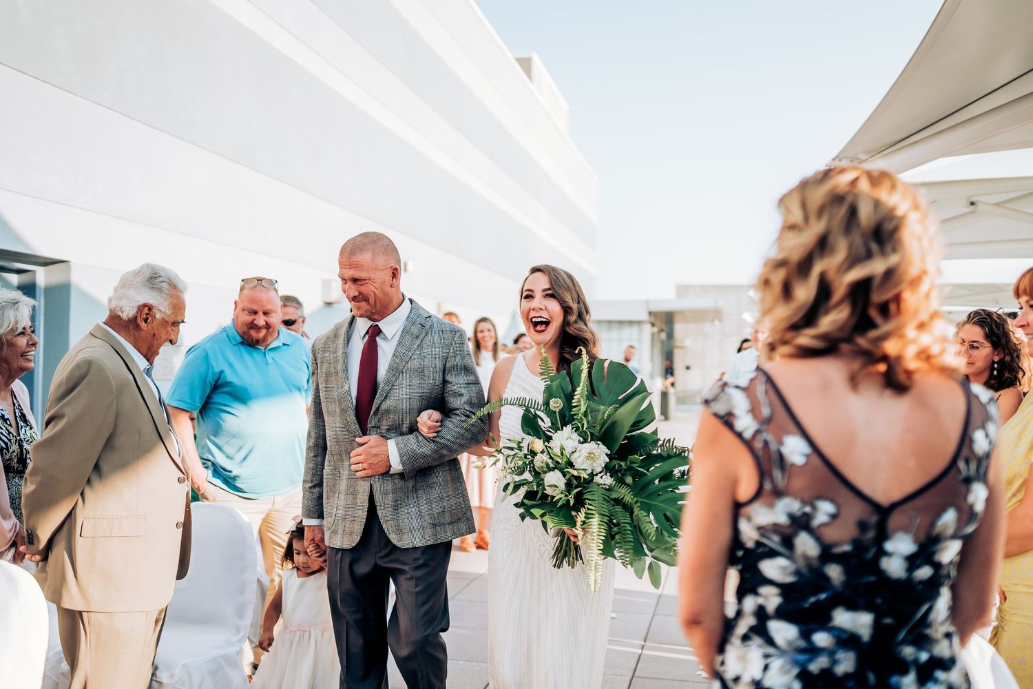 Joyful outdoor wedding reception with guests celebrating under white tents.