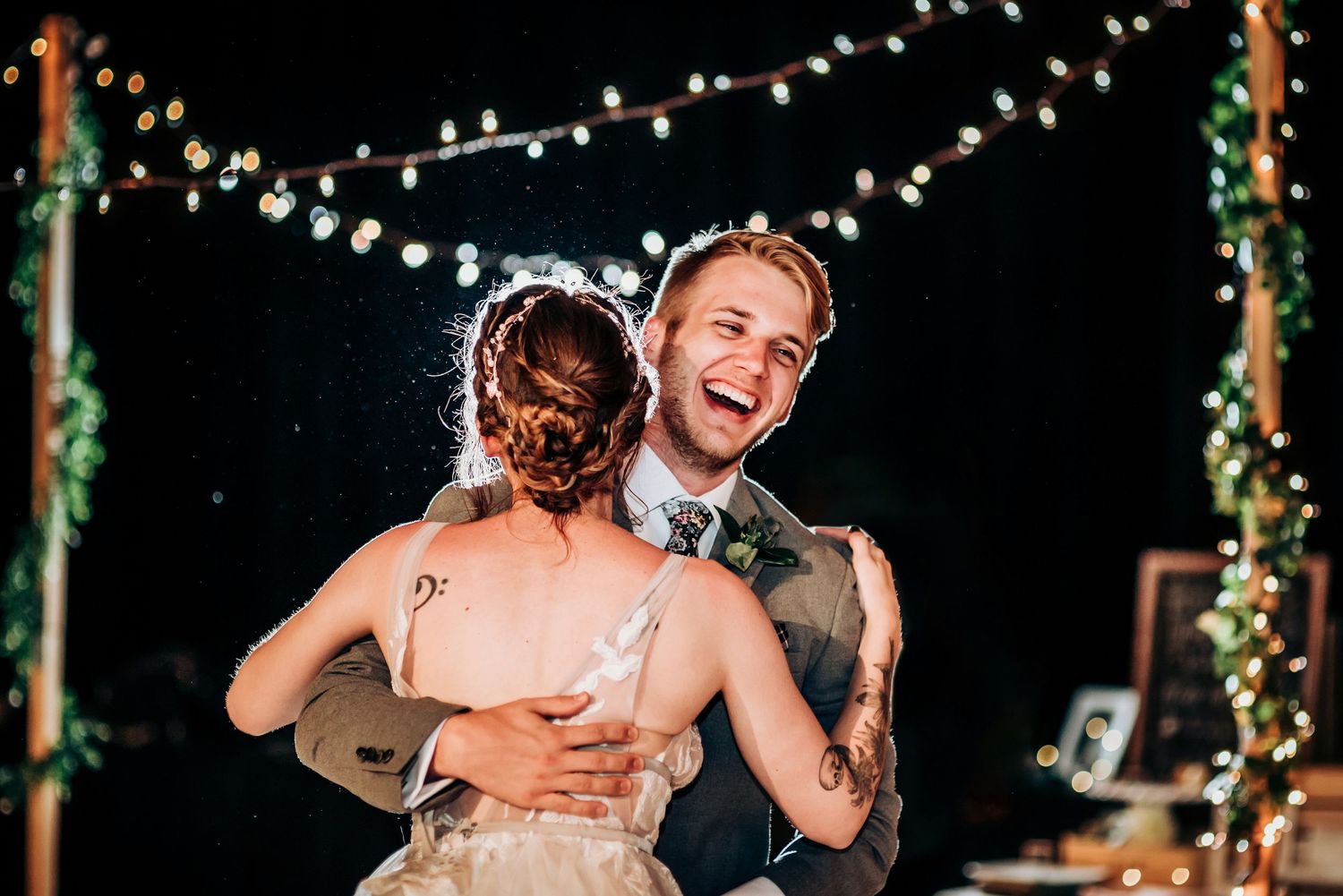 Wedding reception celebration with string lights and dancing under the stars at night.