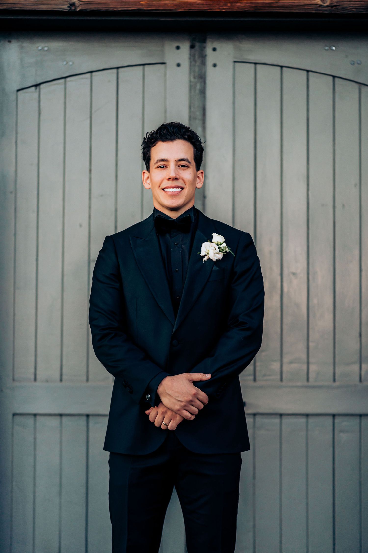 Classic groom portrait in navy suit against gray doors at wedding venue.