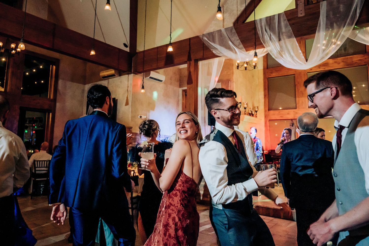 Wedding guests dance and socialize at an elegantly decorated indoor reception venue.