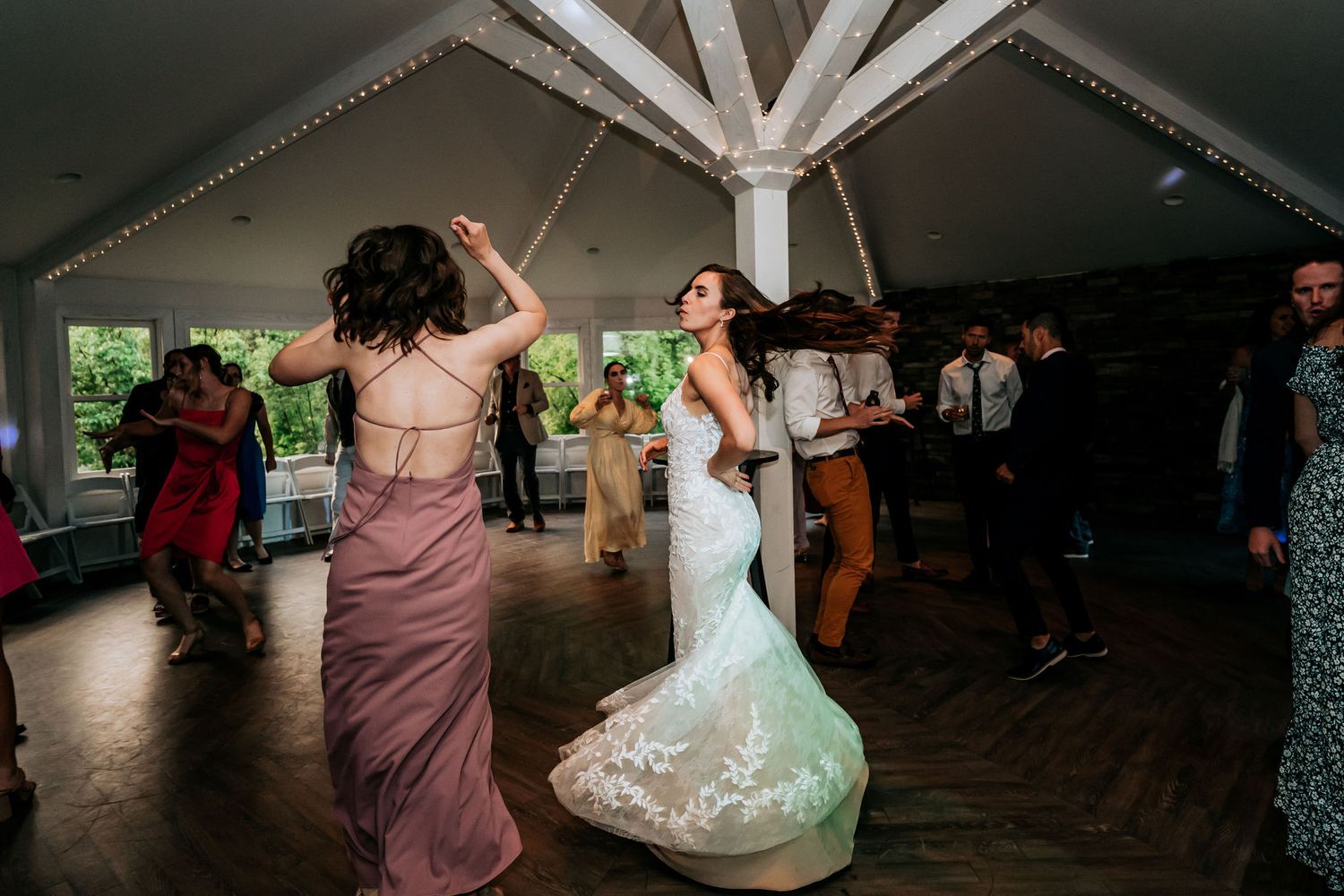 Joyful dancing at a tented wedding reception with white timber beam details.
