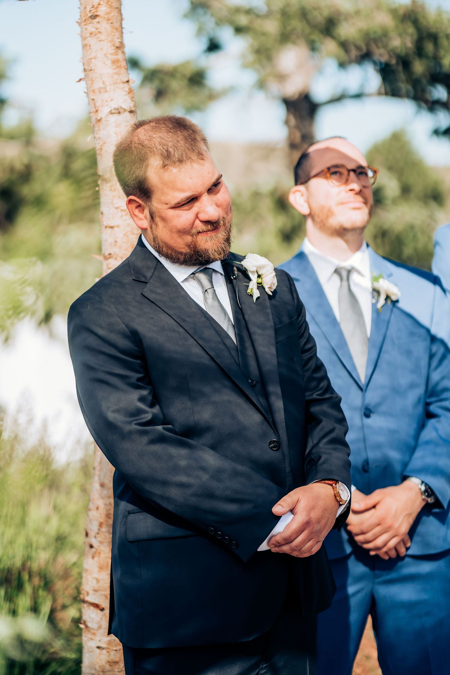 Groomsmen share emotional moment during outdoor wedding ceremony.