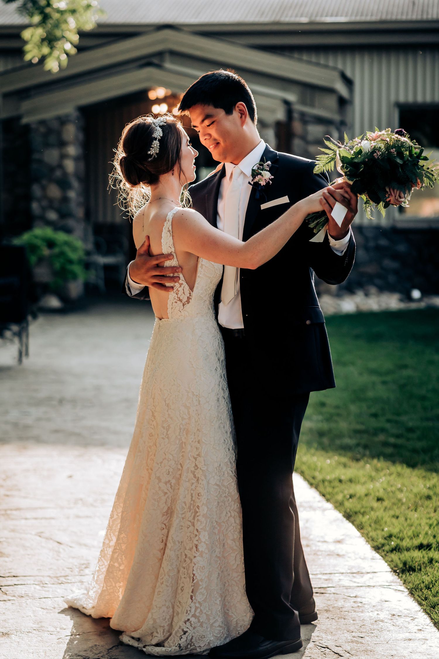 Elegant wedding couple sharing intimate dance moment on stone pathway.