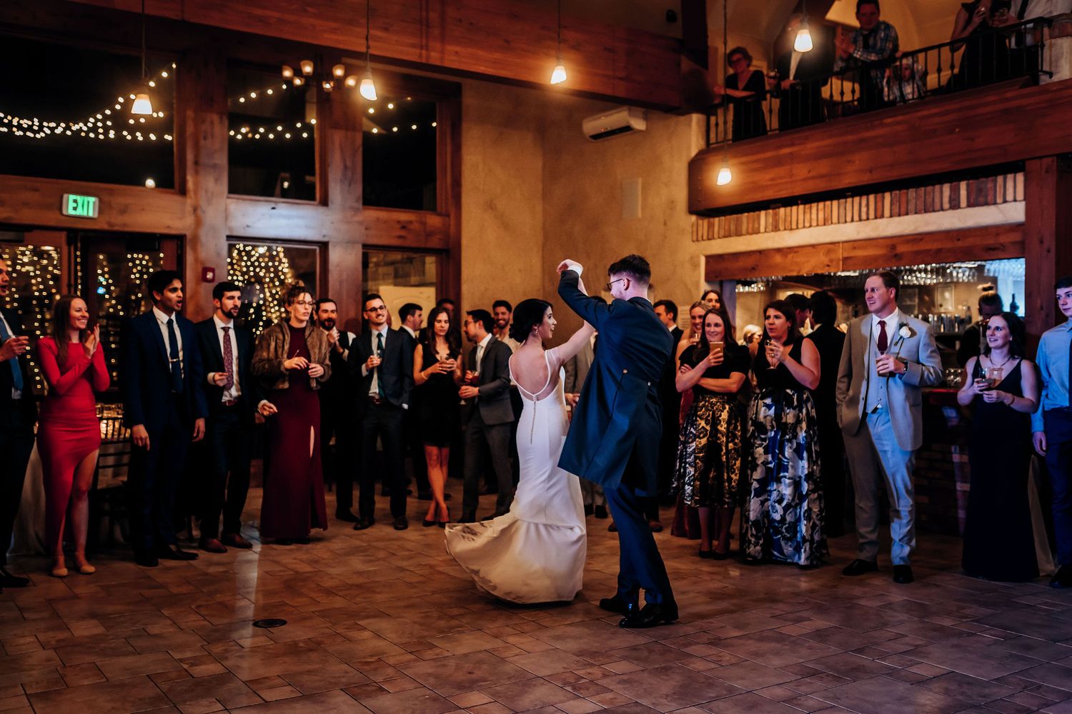 Newlyweds performing their first dance surrounded by guests in an elegant reception venue.