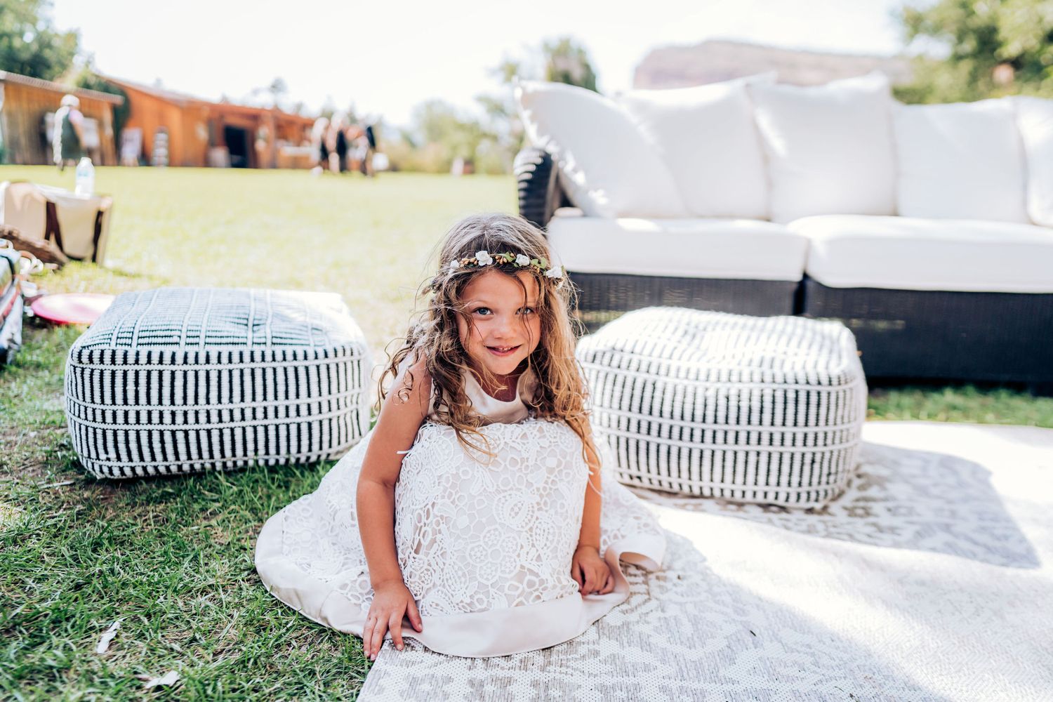 White and gray pouf ottomans arranged near outdoor lounge seating on a sunny lawn.