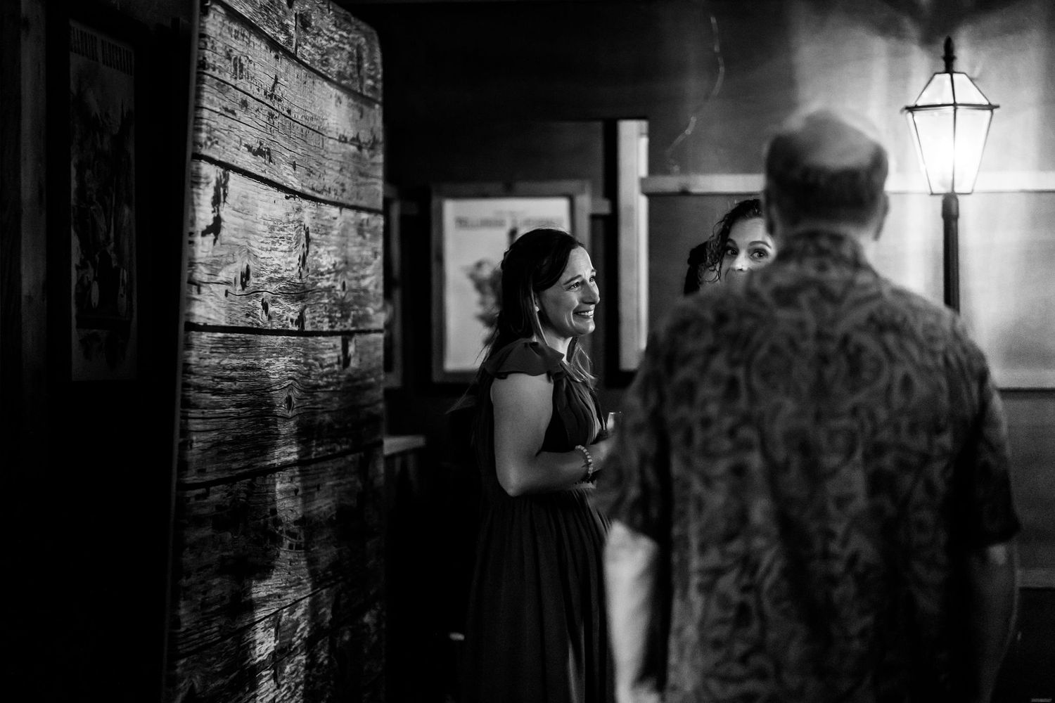 A black and white candid moment captured in a rustic indoor wedding venue.