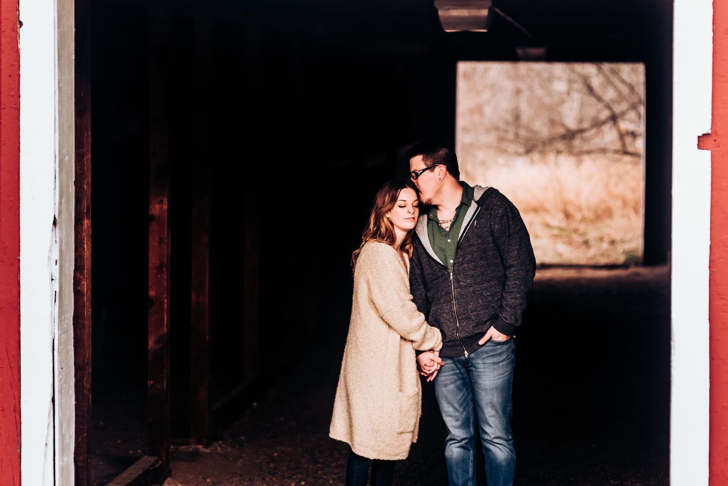 A couple shares an intimate moment inside a dark doorway.