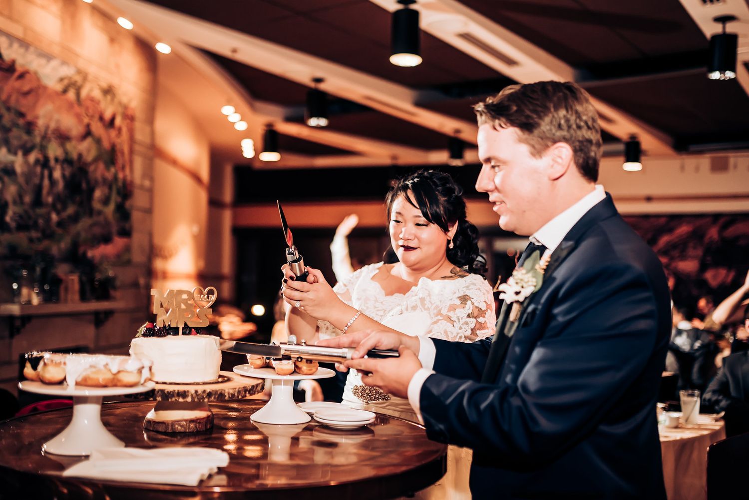 Couple sharing dessert and laughter at their wedding reception table.