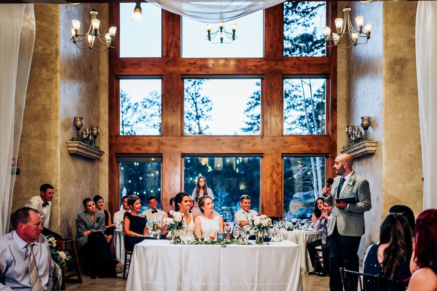 Wedding reception hall with cross-beam windows and guests seated at decorated tables.