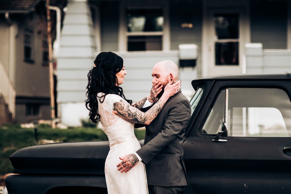 A romantic wedding moment captured next to a vintage black car.