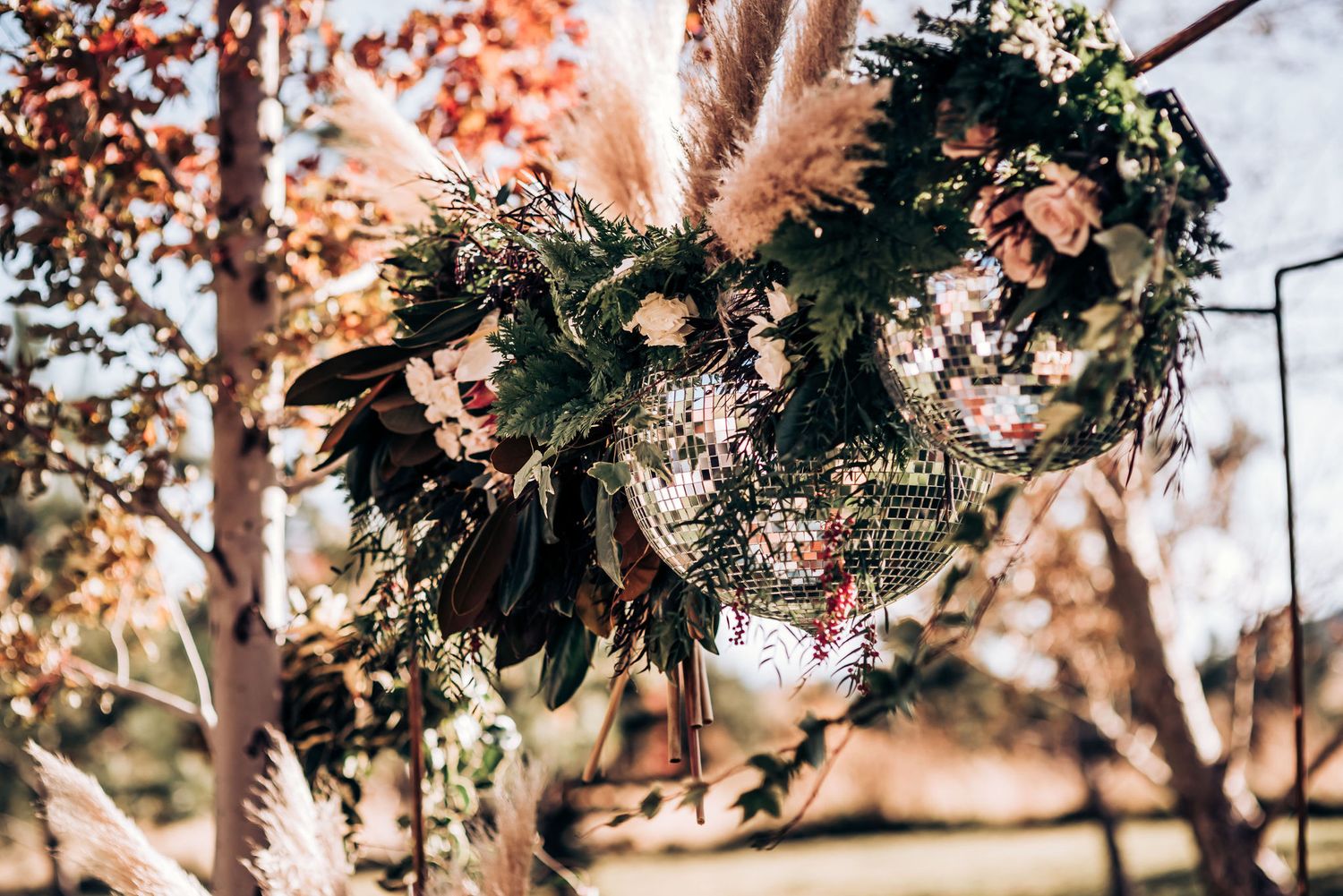 Modern wedding floral arrangement featuring dark greenery, dried pampas grass, and delicate pink blooms.