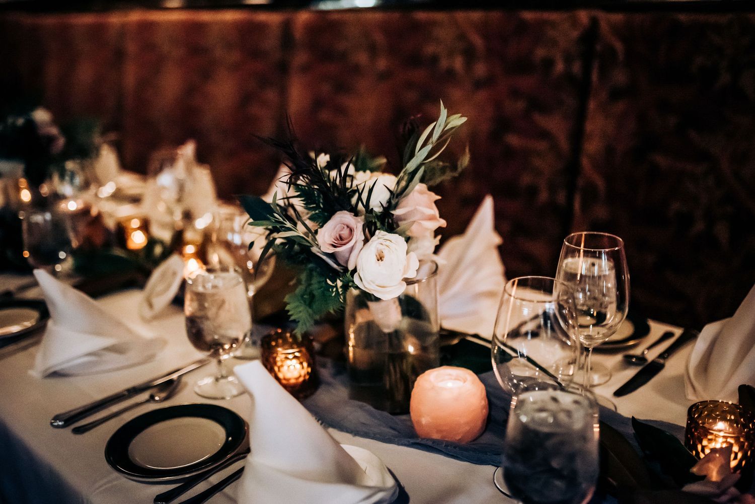 Romantic wedding tablescape with pink roses, candles and elegant place settings.