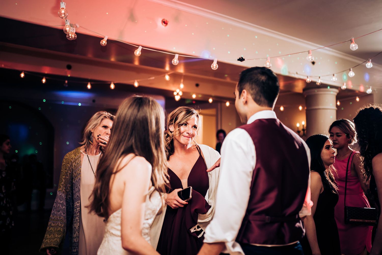 Guests mingle and chat during an evening celebration in a warmly lit indoor venue.