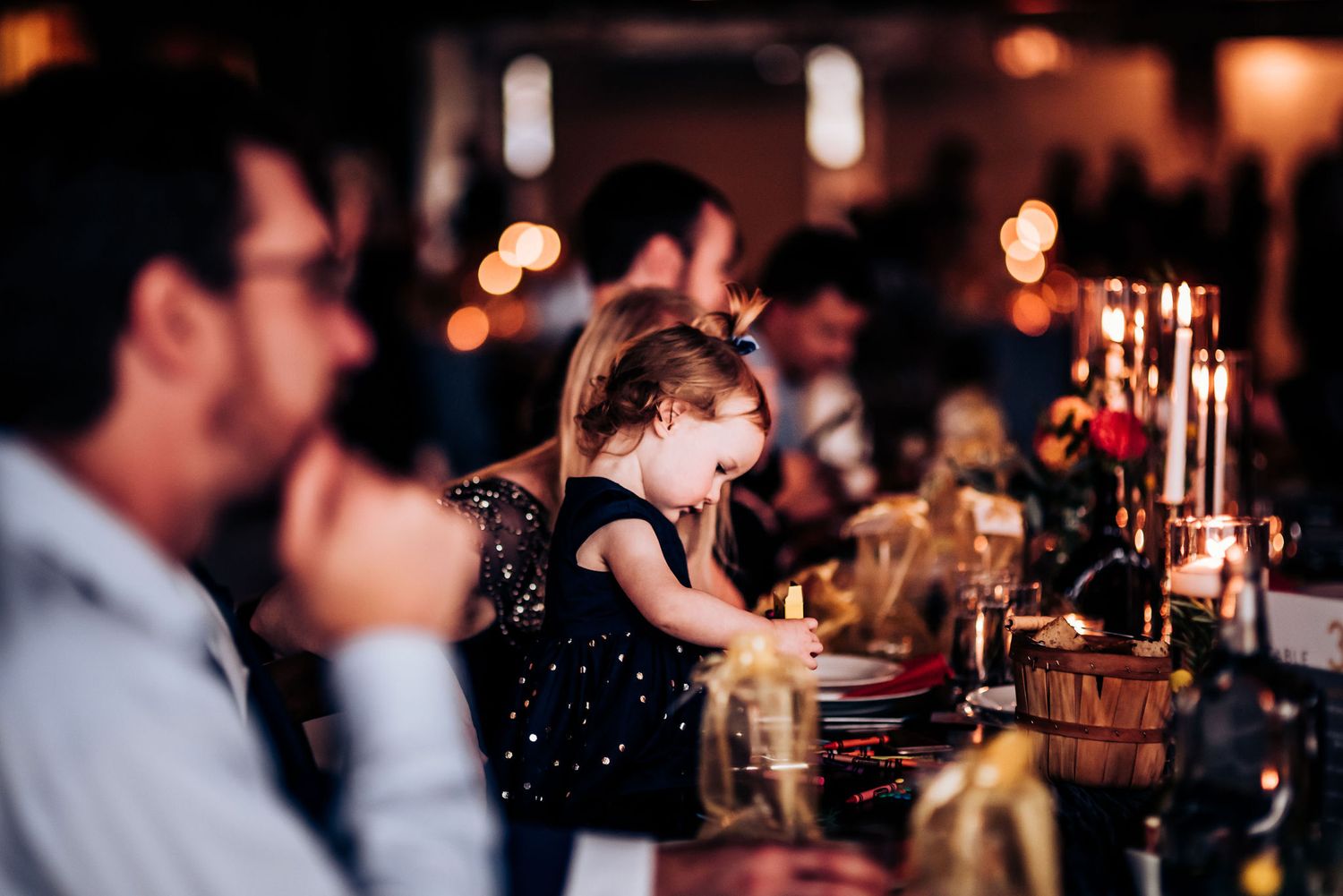 Patrons seated at a cozy dimly lit bar with atmospheric lighting and glassware.