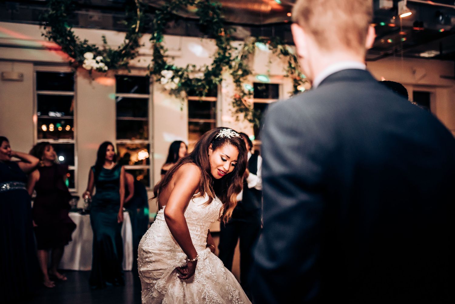 A couple shares a romantic dance moment at their wedding reception with festive decorations.