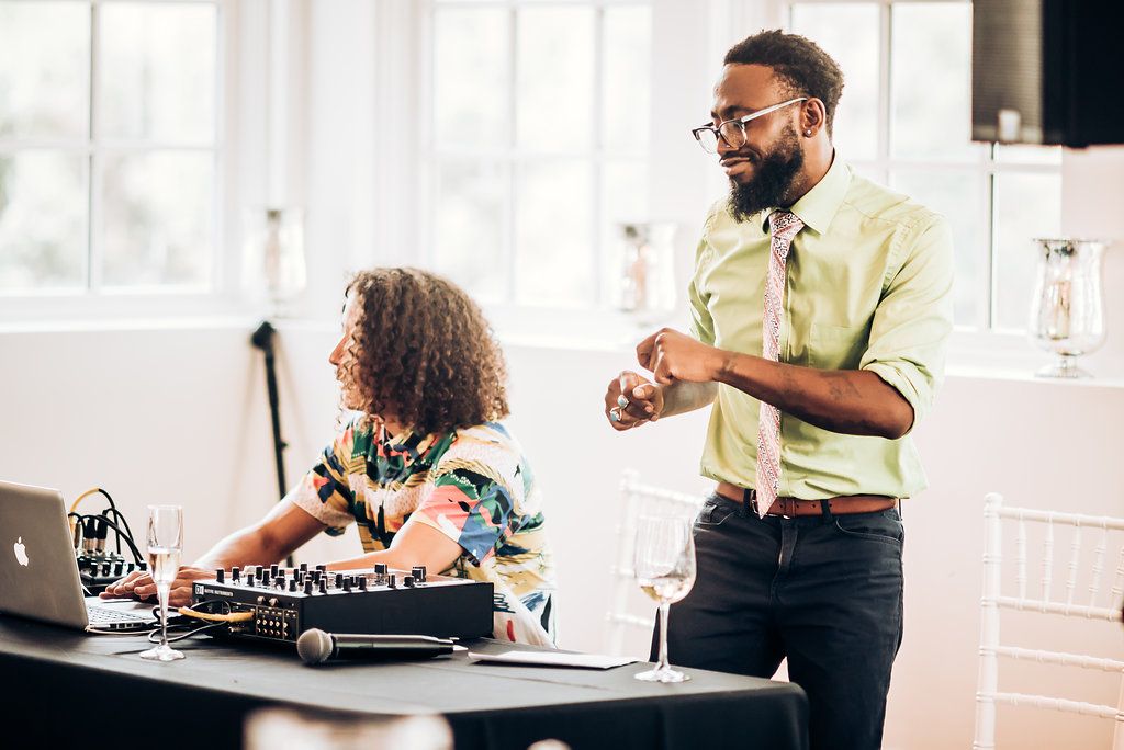 DJ duo setting up equipment and preparing music at bright indoor venue.