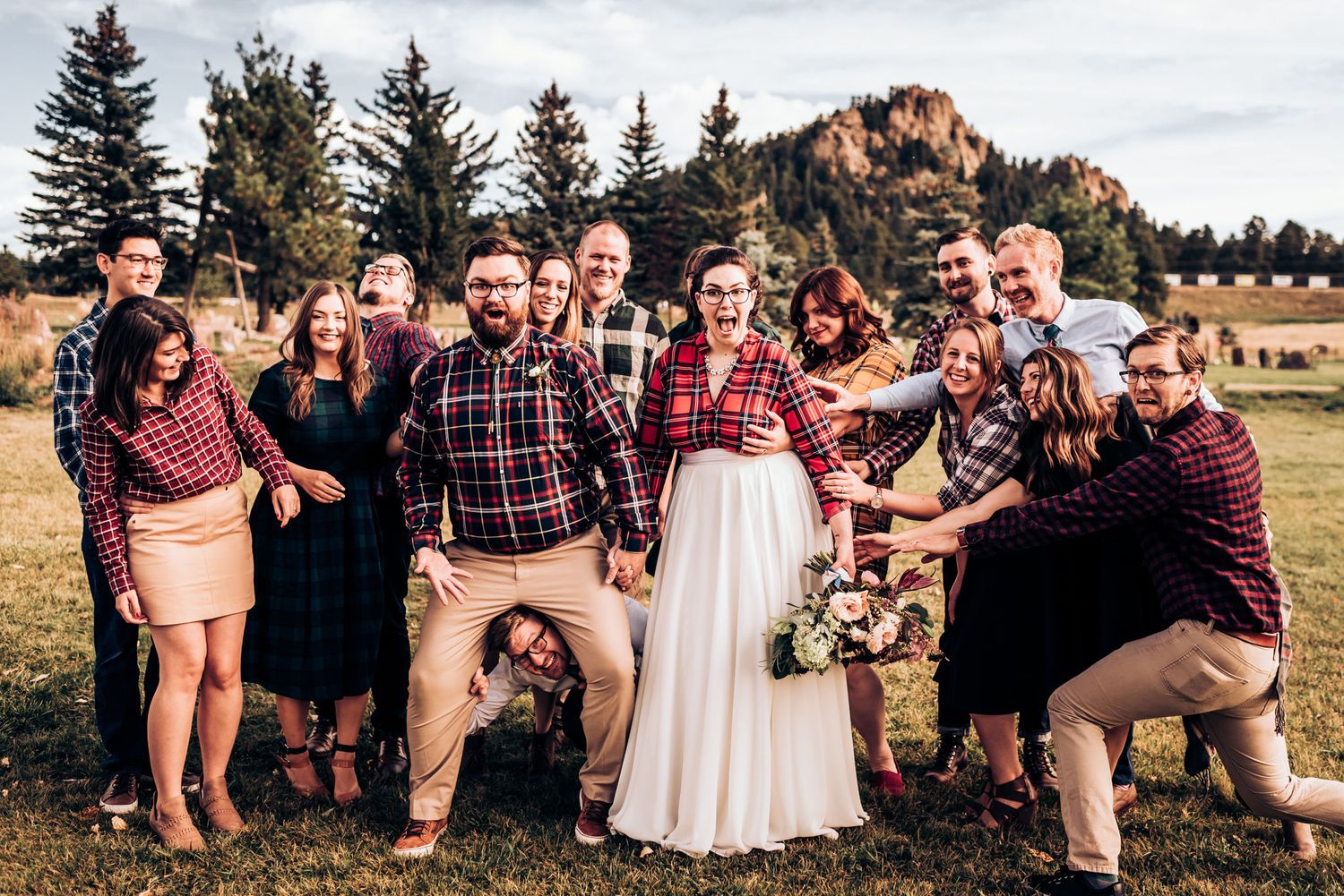 Wedding group photo with mountain scenery showing casual attire and plaid theme.
