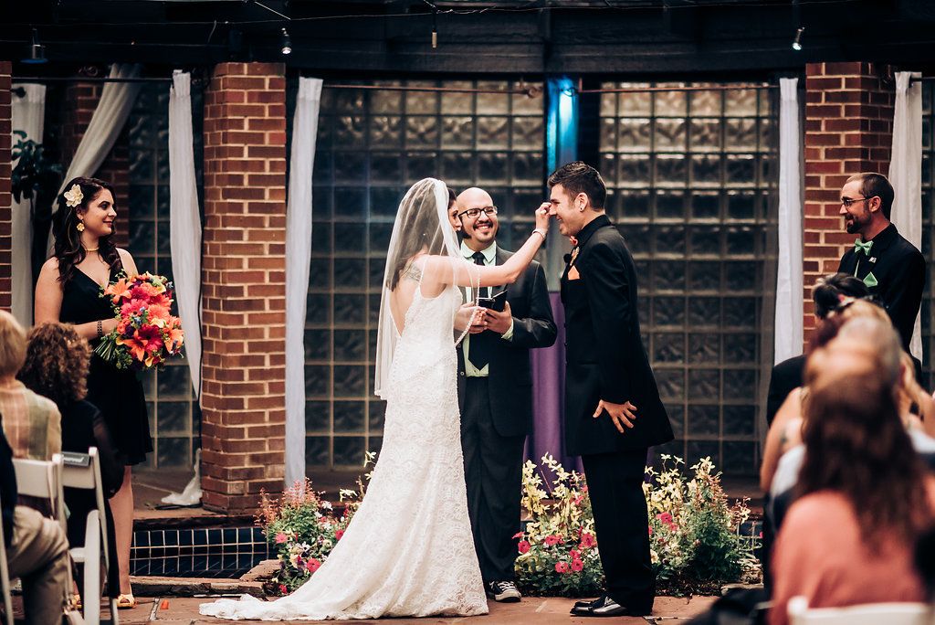 Joyful moment during wedding ceremony at brick venue with floral decorations.