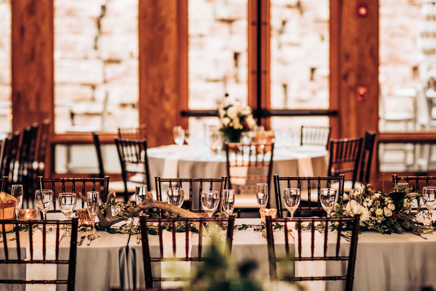 Elegant wedding reception setup with dark Chiavari chairs and white tablecloths.