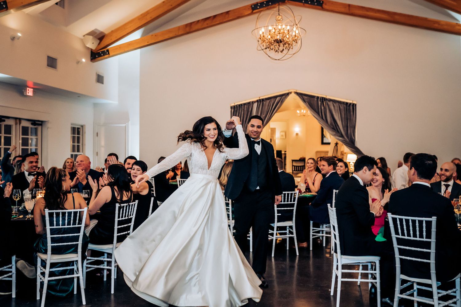 Reception celebration in a venue with wooden beams and elegant white chairs.