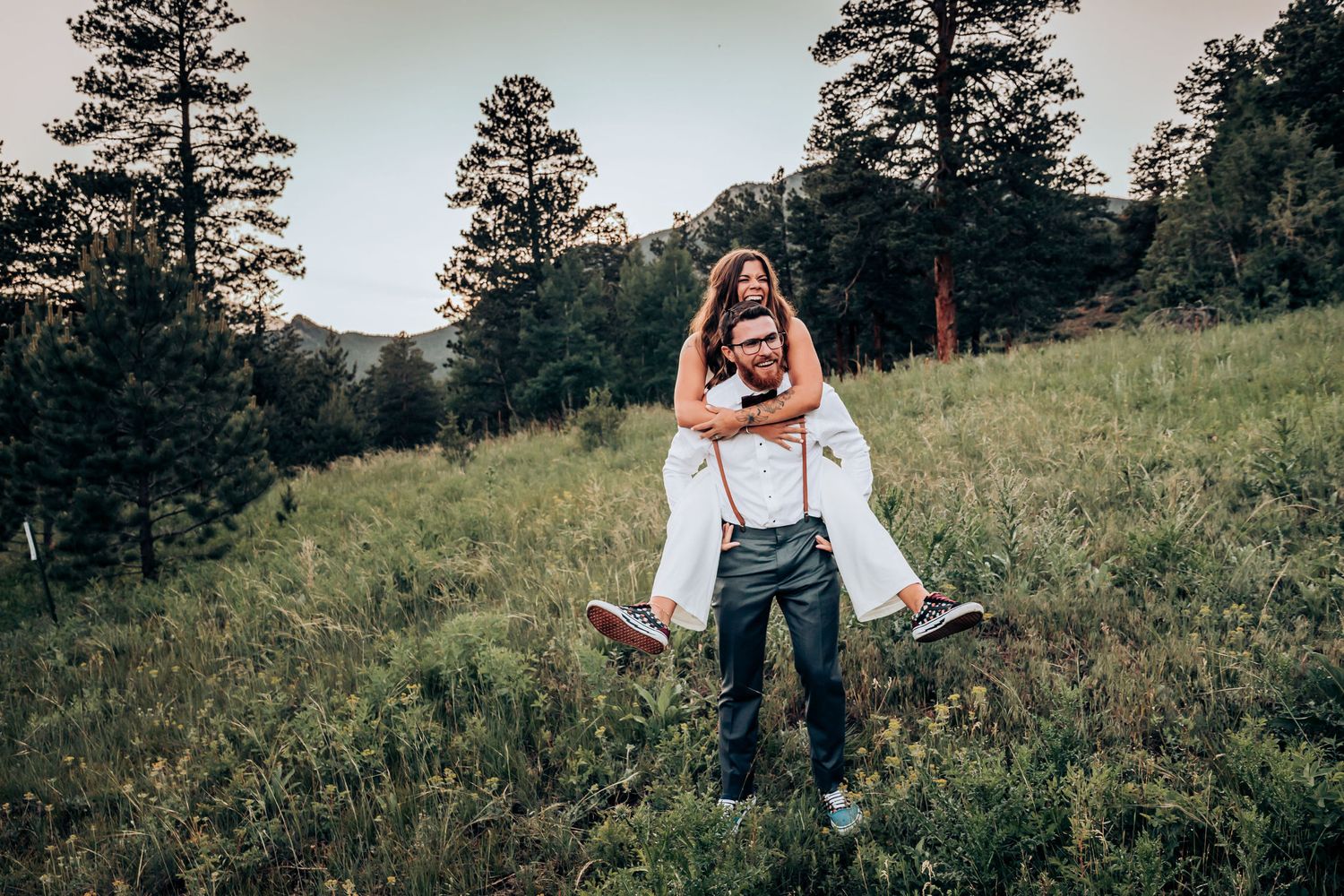Playful outdoor wedding photoshoot with a couple in a scenic mountain setting.