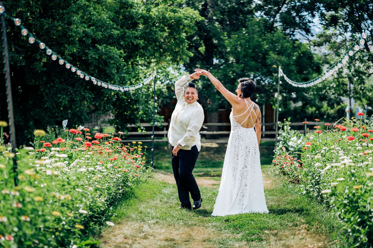 A couple dances in a garden path lined with wildflowers and string lights.